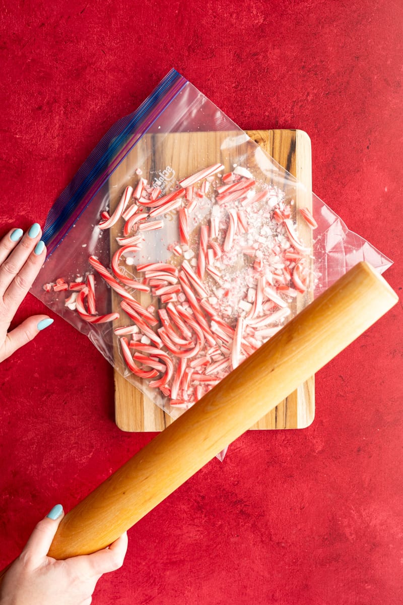 Candy canes that have been unwrapped are in a ziplock bag being smashed with a rolling pin.