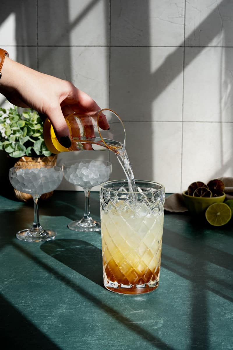 Adding silver rum to a cocktail shaker to make classic Cuban daiquiris.