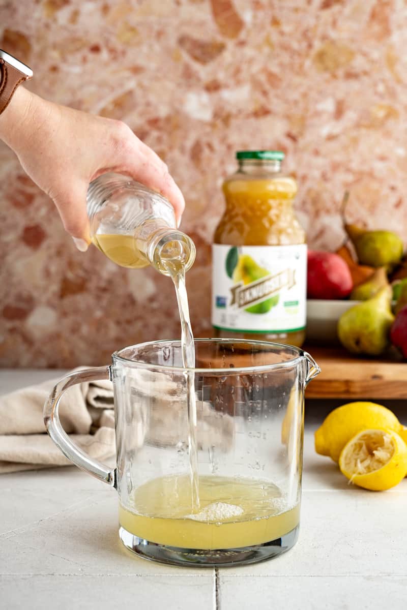 Adding cardamom simple syrup to lemon juice.