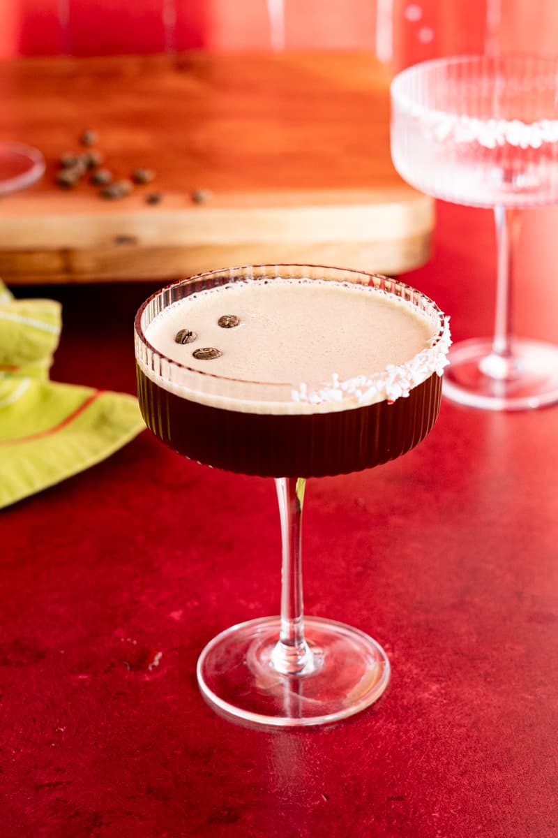 A garnished peppermint espresso martini is prepared for serving and garnished with three espresso beans.