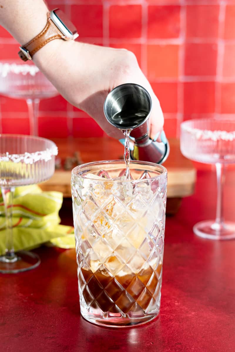 Adding vanilla vodka into a cocktail shaker.