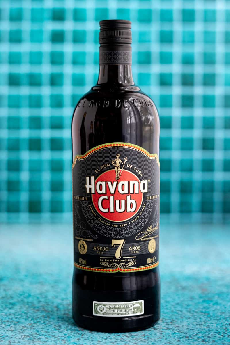 A bottle of Havana Club 7 Year Aged Cuban Rum sits on a teal countertop.