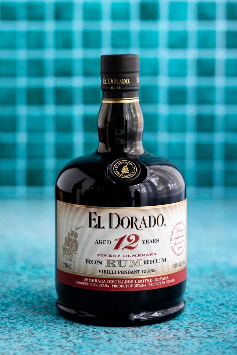 A bottle of El Dorado 12 Year Aged Demerara Rum sits on a teal countertop.