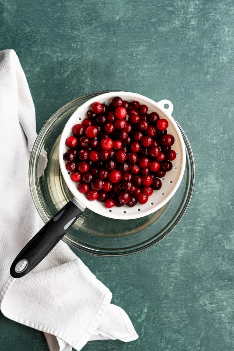 Washing cranberries and straining them through a strainer.