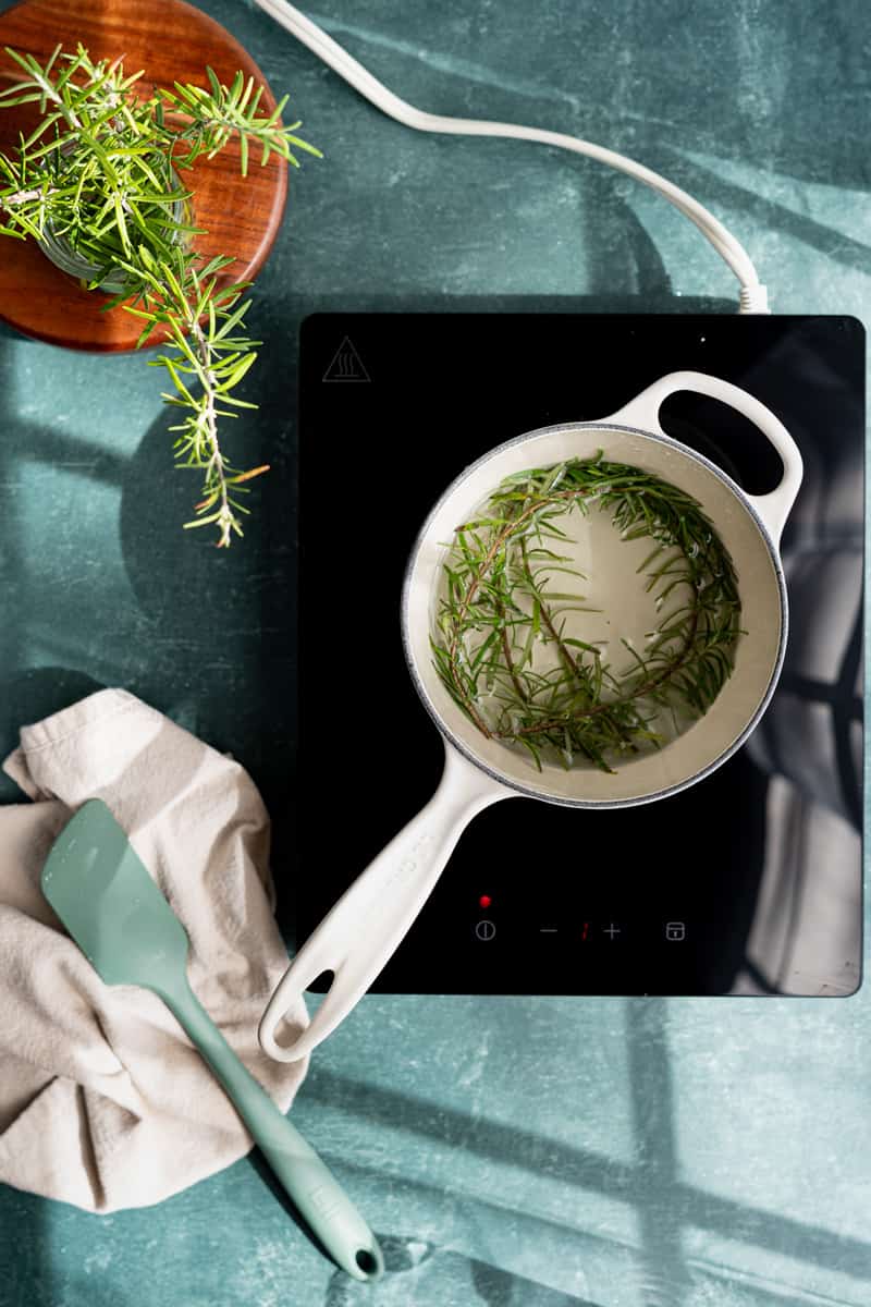 Fresh sprigs of rosemary sit in a pot of simple syrup over low heat to infuse.