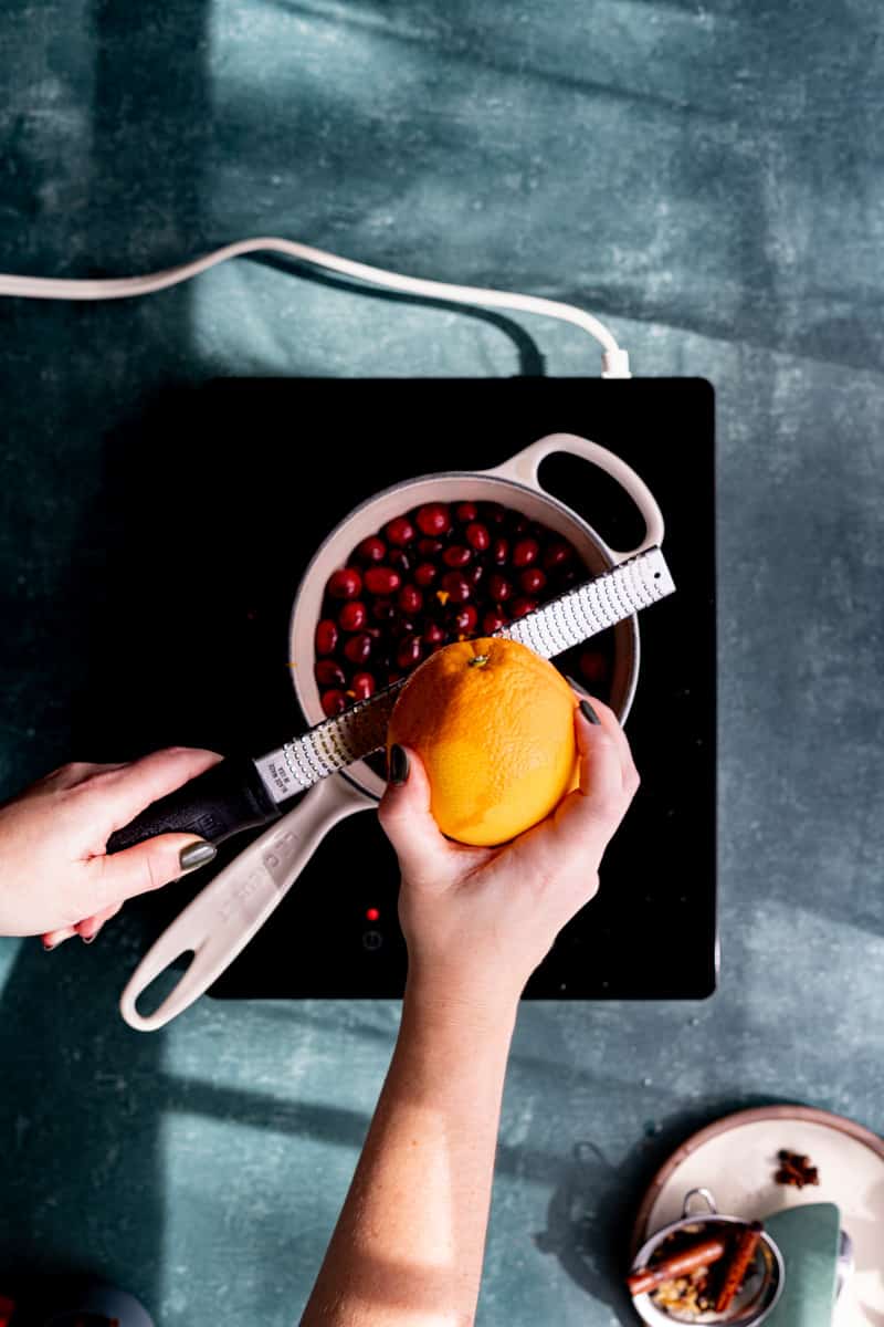 Zesting an orange into the saucepan.