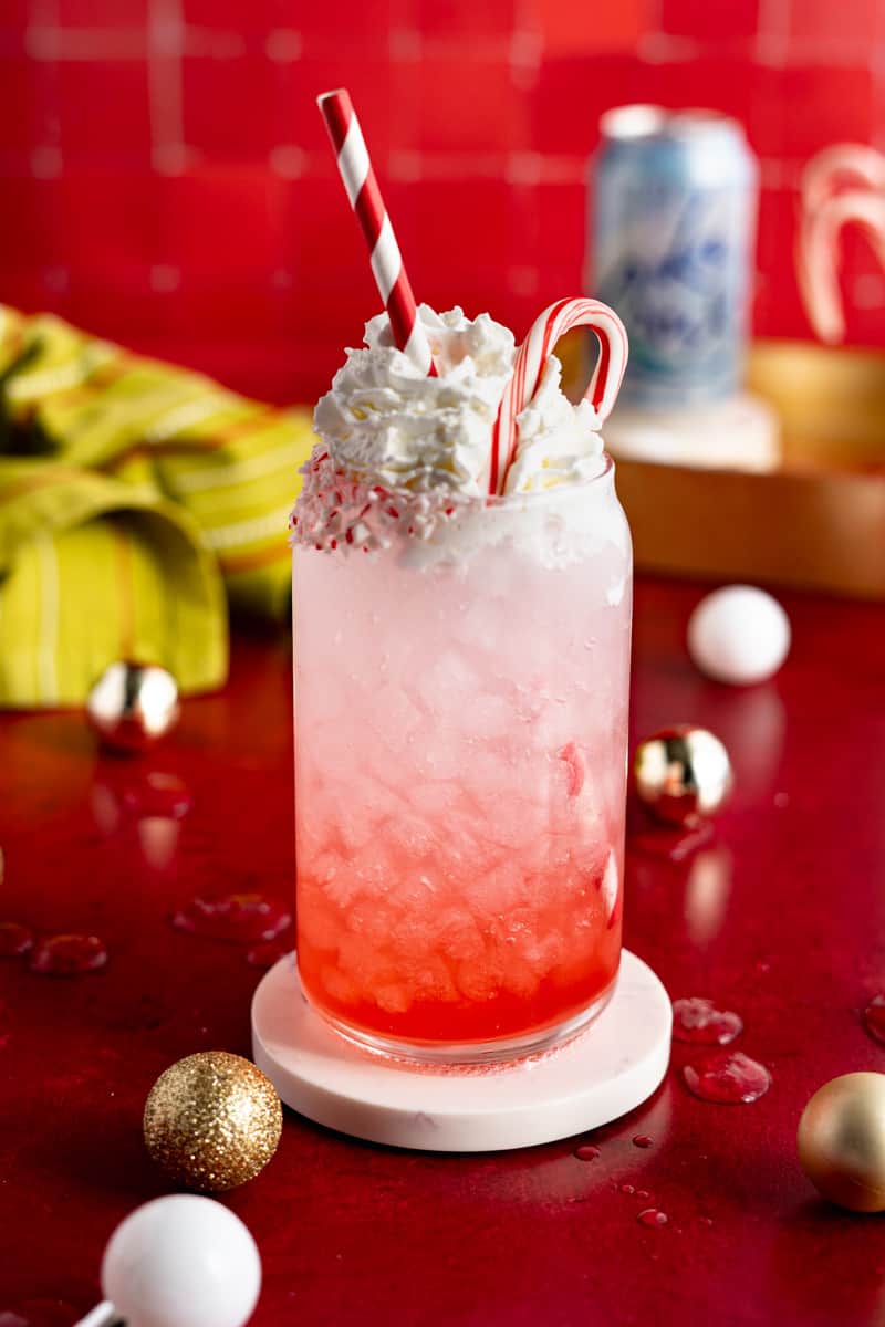 A candy cane soda is garnished with a miniature candy cane.