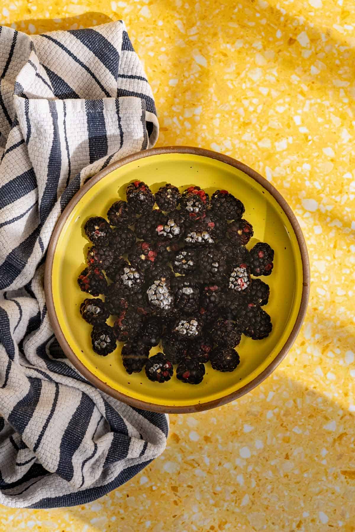 Washing blackberries in a yellow ceramic bowl.