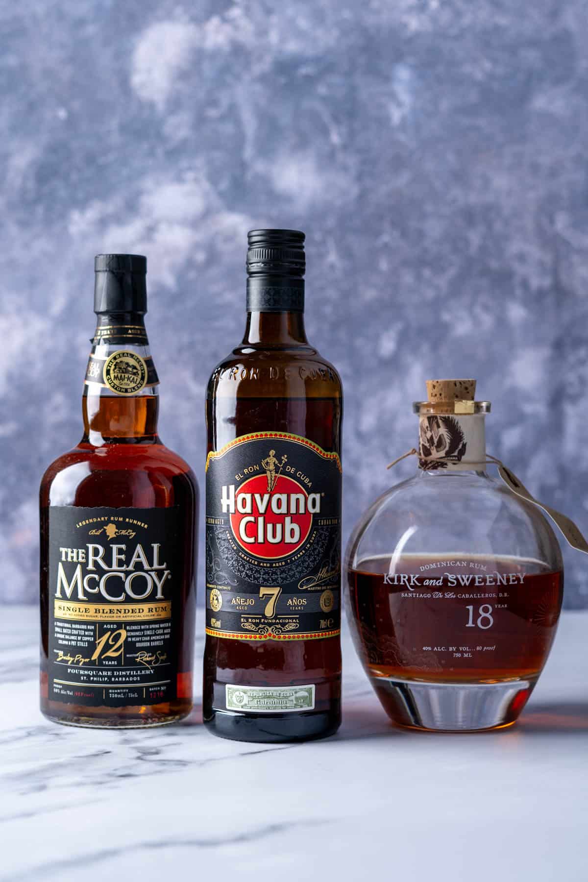 Three bottles of aged rum sit on a counter top.