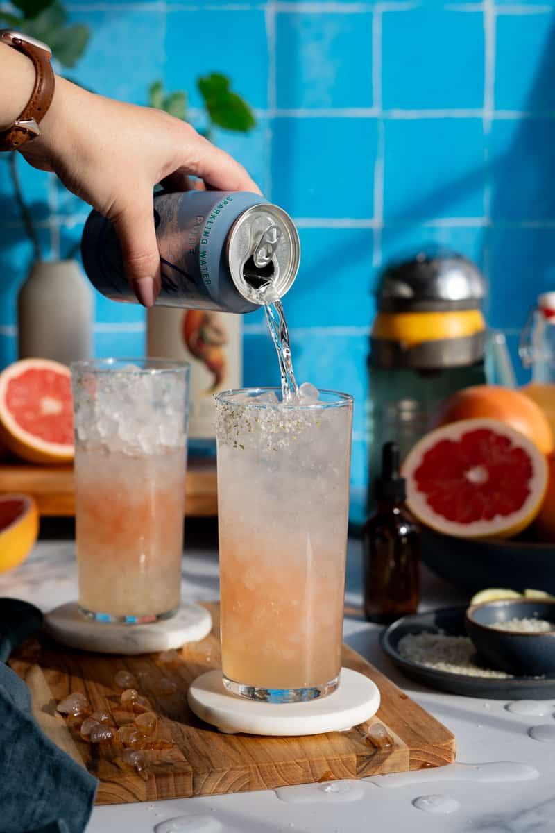 Topping a paloma mocktail with seltzer water.