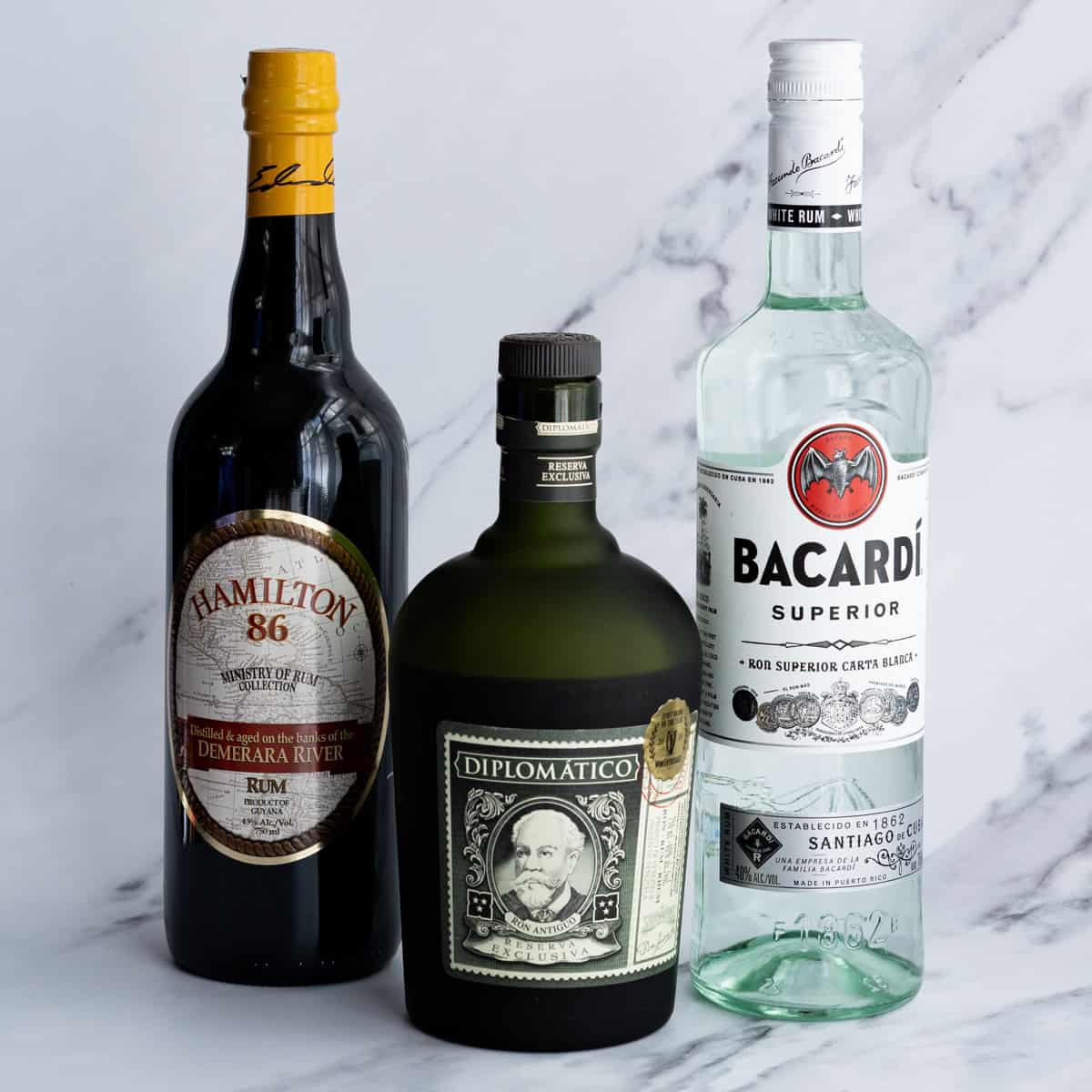 A selection of rums, including light, dark, and aged rum, sit on a marble countertop.