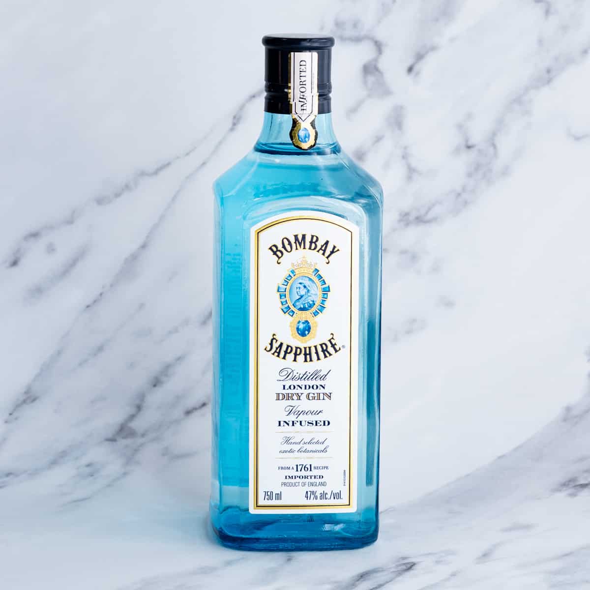 A bottle of gin sits on a marble countertop.