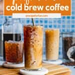 Three glasses of cold brew coffee with ice and swirls of cream on a wooden tray, coffee beans and a jar of cold brew in the background. Text overlay highlights how to make cold brew at home and save money.