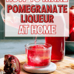 A glass of red pomegranate liqueur with ice sits in front of a carafe, surrounded by fresh pomegranate halves. Text reads, Discover how to make pomegranate liqueur at home—craft your own homemade liqueurs with ease!.