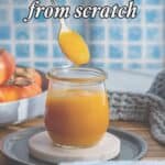 A hand dips a spoon into a jar of persimmon jam on a plate. Text reads, “How to make persimmon jam from scratch. Made with only 3 ingredients and ready in less than 60 minutes!” Persimmons and a towel are in the background.