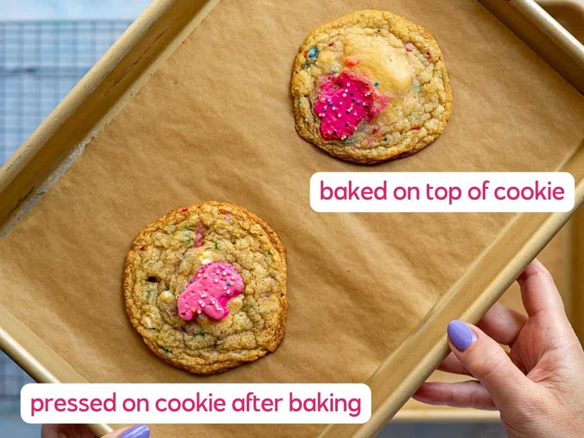 A hand holds a baking tray with two cookies on parchment. One cookie has a circus animal cookie baked inside; the other has the circus animal cookie pressed on top after baking. Labels identify the differences.